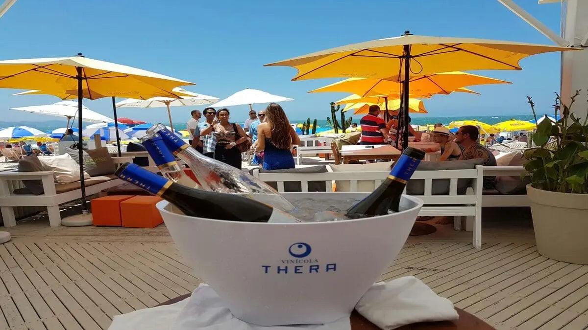 a imagem mostra algumas garrafas dos vinhos Thera em uma praia